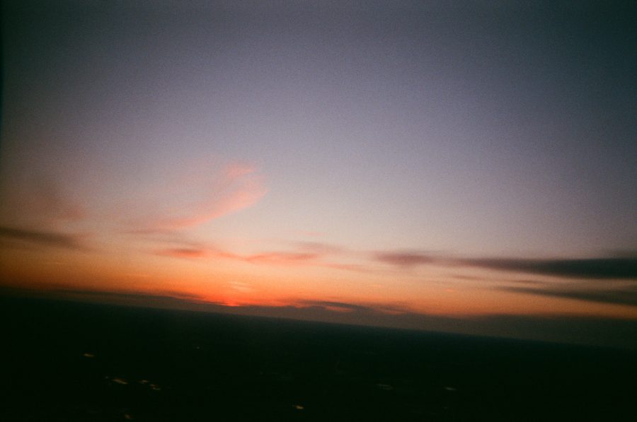 A vibrant sunset as seen from the ground, with a gradient sky transitioning from warm orange and pink near the horizon to darker shades of blue at the top.