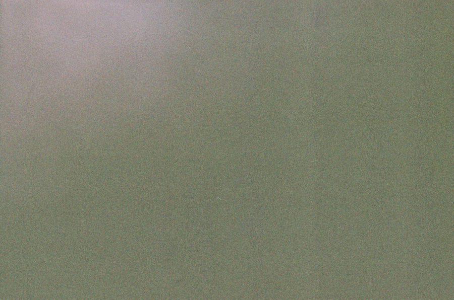 An underexposed image with a grainy texture. The frame is dominated by abstract hues of green and gray, with faint hints of light creating an ambiguous yet intriguing composition. Disposable camera fun.