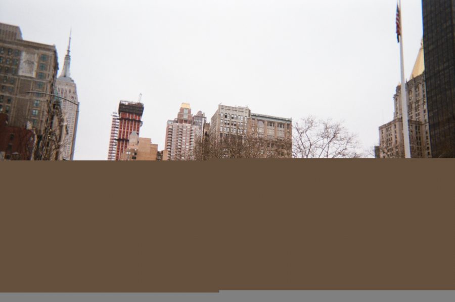 A half-glitched image of the New York City skyline. The top portion of the photo features sharp lines of buildings, including nearby construction. The bottom half is eaten up by a flat brown distortion, creating a surreal juxtaposition between the digital glitch and the architectural details. There's a strip of grey distortion at the very bottom.