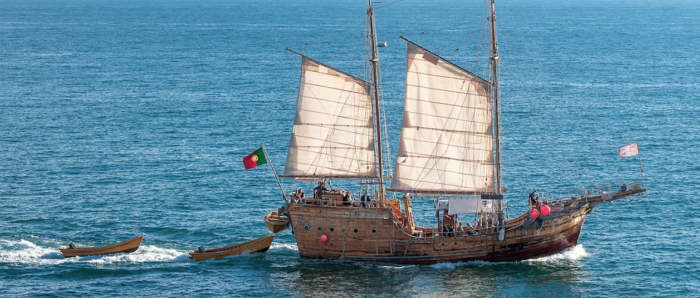 an actual flagship, with flags and sails raised, on the water