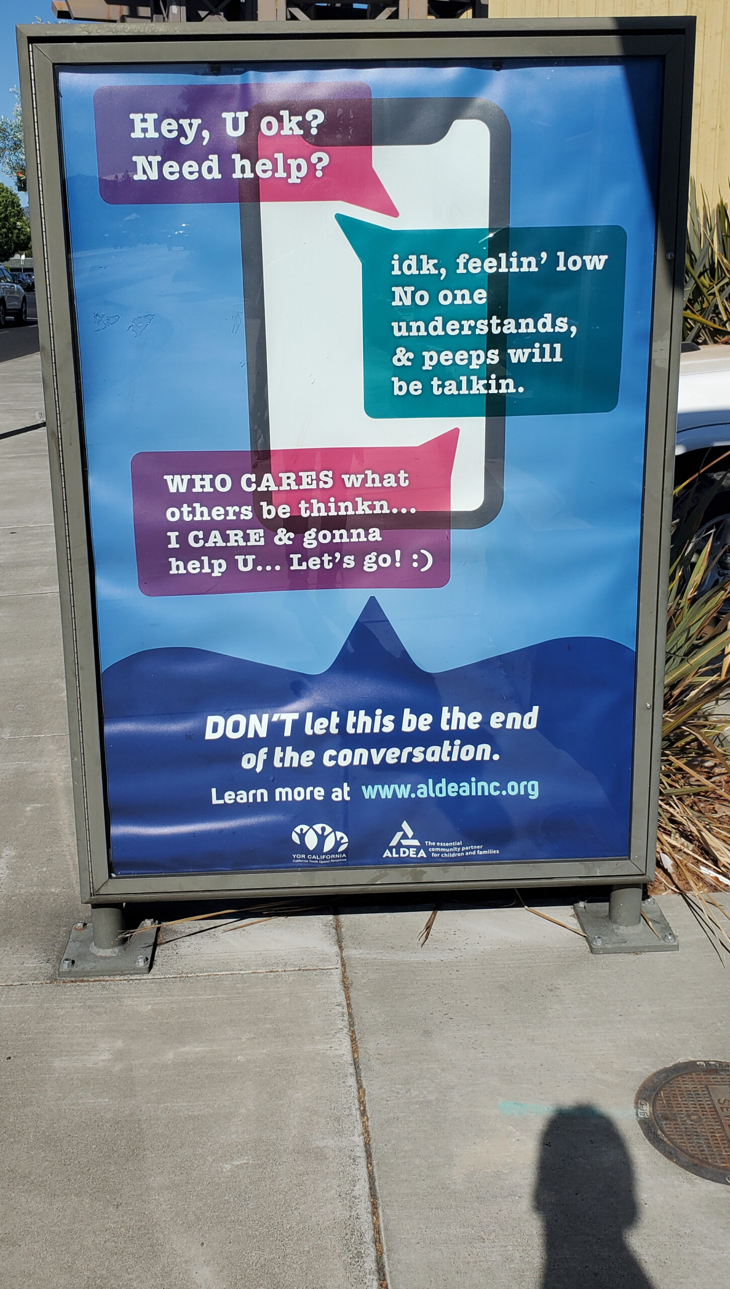 A large ad on the sidewalk with terrible ad copywriting.