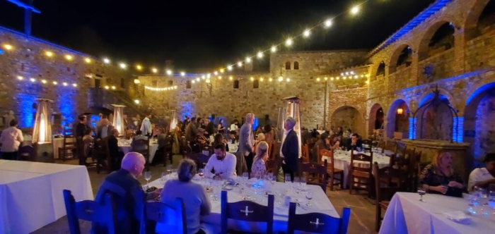 Nighttime dinner and wine at the castle, lit by overhead lights and blue lanterns.