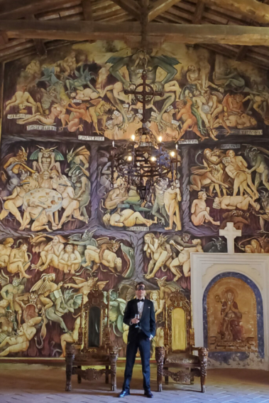 Ethan J. Hulbert in front of Medieval Satan wall fresco.
