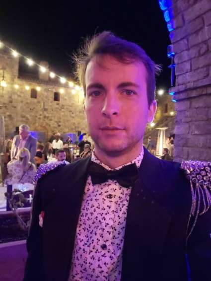 Ethan James Hulbert in a suit and bowtie and spikes at the castle masquerade ball dinner at night.