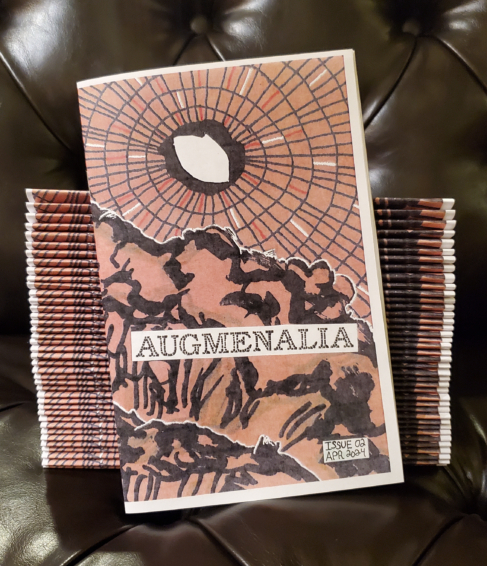 The cover of Augmenalia Issue #02 against a stack of them.