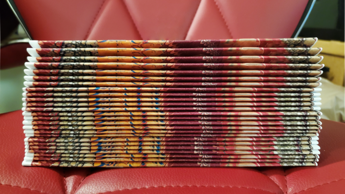 A stack of 25 copies of Augmenalia Issue #3, showing how their spines line up down the sides. This is the entire first print run, before distribution.